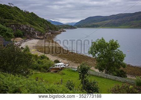 A Boat Resting On The Shores Of Loch Broom Off The Harbor Of Ullapool, Scotland, On A Cloudy Morning