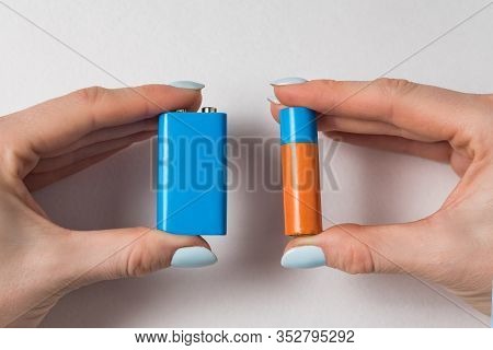 Aa And Pp3 Alkaline Batteries In The Womens Hands. Generic Accumulator On White Background. Copy Spa