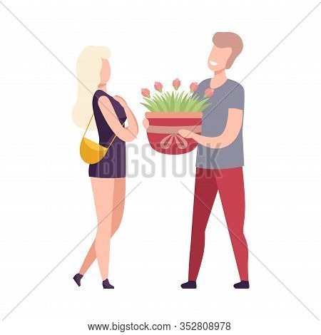 Man Giving Pot With Blooming Flowers To Beautiful Young Woman, Romantic Couple In Love On Date, Holi