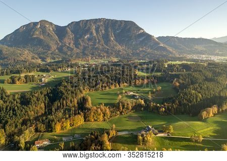 Aerial View Of Green Meadows With Villages And Forest In Austrian Alps Mountains.