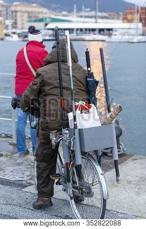 Detail Of A Man On Top A Bicycle With Fishing Rod Going To Fish In A Harbour