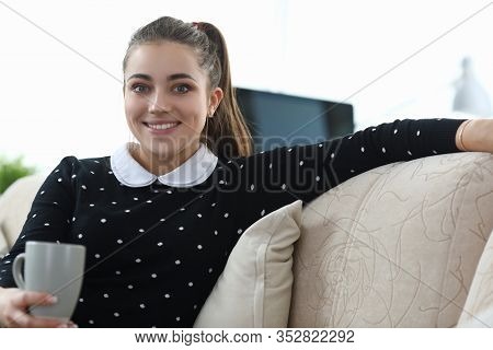 Beautiful Girl Posing While Sitting Sofa Apartment. Girl Fully Enjoys Loneliness. Learns To Notice A