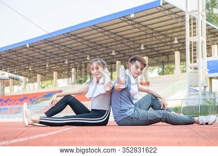 Portrait Of A Cute Hispanic Couple Holding Water And Resting After Runnng On Track At Studium, Healt