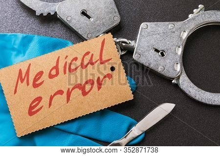 Handcuffs, A Scalpel And Medical Gloves On The Table. View From Above. Medical Error Concept