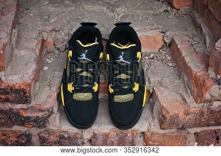 Nike Air Jordan Iv 4 Retro Basketball Shoes In Yellow And Black Colorway Shot Outdoors On An Old Red