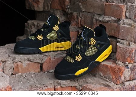 Nike Air Jordan Iv 4 Retro Basketball Shoes In Yellow And Black Colorway Shot Outdoors On An Old Red
