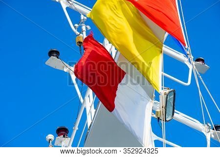 Quarantine And Pilot Flags Flying In Strong Winds On A Blue Day On A Cruise Ship With Navigation Lig