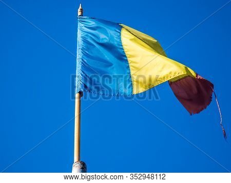 Worn Romanian Flag In The Wind  On The Mast.