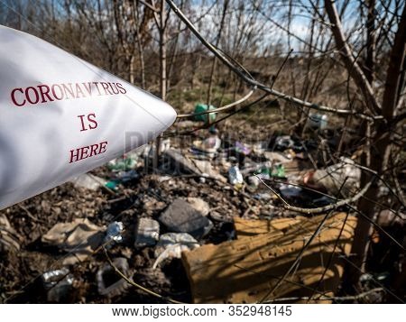 White Paper With The Inscription Corona Virus Is Here Pointing To A Pile Of Trash. Environmental Awa