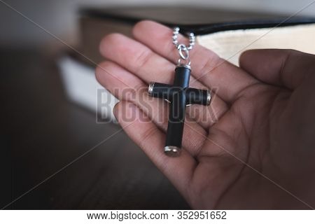 The Crucifix Lay On The Palm Of The Hand,bible Background And Close-up Images Of Praying For The Ble
