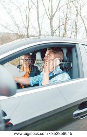 Driving instructor being rather mad at student using his telephone while driving