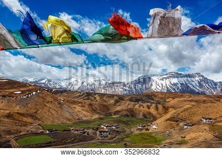 Prayer flags with Buddhist mantra on them in sky over Comic Village. Spiti Valley, Himachal Pradesh, India