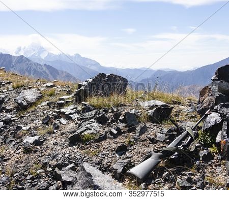 Hunting Rifle With Optical Sight And Bipod On The Rocks In The Mountains. Hunting Weapons For Target