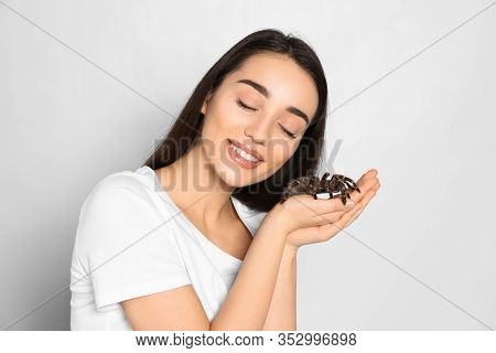 Woman Holding Striped Knee Tarantula On Light Background. Exotic Pet