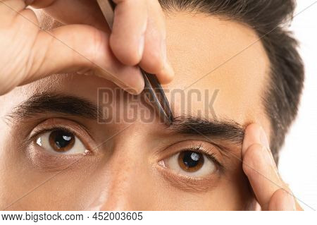 Male Eyes And Tweezers For Eyebrow Shape Correction