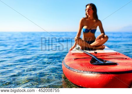 Beautiful Woman Practising Yoga On Paddle Sup Surfboard