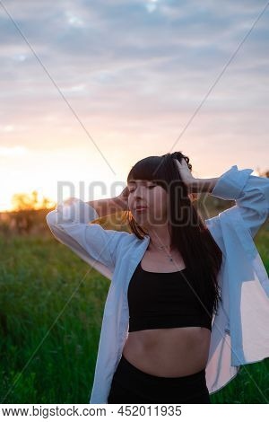 Brunette Woman In White Blouse With Baldric On Summer Field On Sunset. Peaceful Time. Millennial Gen