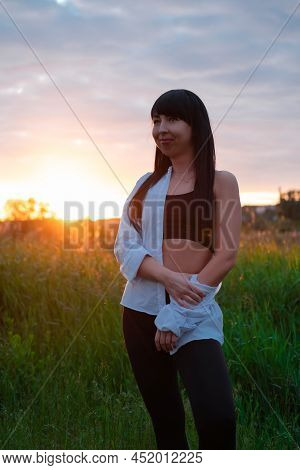 Brunette Woman In White Blouse With Baldric On Summer Field On Sunset. Peaceful Time. Millennial Gen