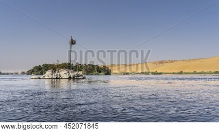 A Small Rocky Island Is Visible On The River. There Is Green Vegetation On The Shore. Navigation Tow