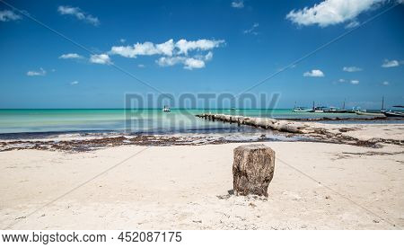 Peaceful Seaside With Calm Turquoise Sea And Rocky Pier With Leisure Boats Anchored Nearby.