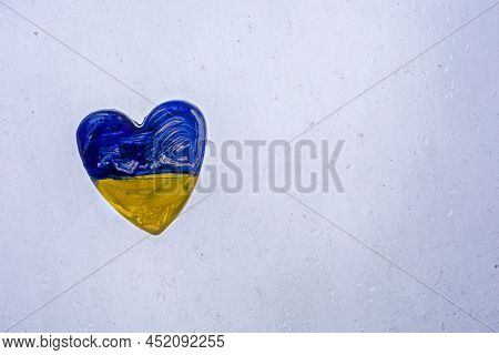 Ukrainian Ceramic Heart Placed Against An Opaque, Muddy Window During Shelling. War In Ukraine