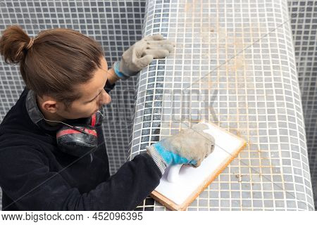 View From Above Of Hypster Man Working Putting Blue Tiles On A Constrcution