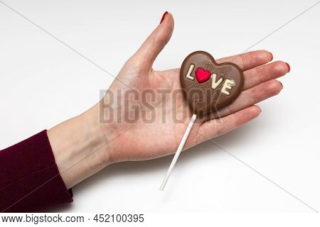 Woman Holding A Chocolate Candy In The Form Of A Heart. High Quality Photo