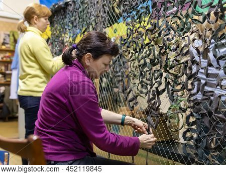 Kyiv, Ukraine - Apr. 01, 2022: A Group Of Volunteers In A Shelter Making Camouflage Net, From Differ