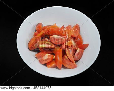 Top View Of Tomatoes Sliced In White Bowl Isolated On Black Background (solanum Lycopersicum Var. Ce