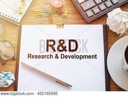 Glasses, Pen, Wrinkled Paper, A Cup Of Coffee, A Calculator And A White Sheet Of Paper With R And D 