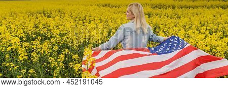 Adult Woman Holding American Flag With Pole, Stars And Stripe In A Yellow Rapeseed Field. Usa Flag F