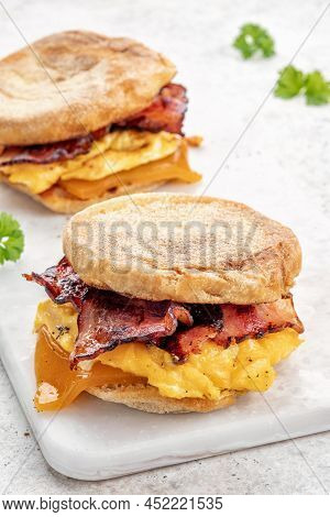 English Muffin, Scrumbled Egg, Ham, And Cheese Breakfast Sandwich On A Cutting Board