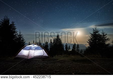 Illuminated Tent Setting Up On Edge Of Stone Trail On Mountain Hill. Incredible Beauty Of Evening La