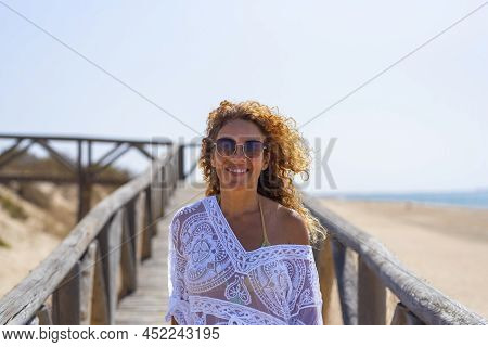 Portrait Of Happy And Cheerful Young Adult Woman Smiiing At The Beach. Confident Tourist And Summer 