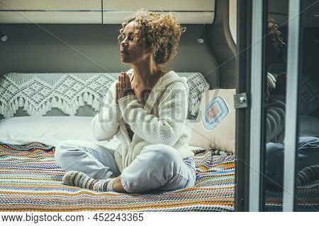 Young Woman In Meditation Activity Sitting On The Bed In Camper Van Bedroom. Serene And Confident Fe