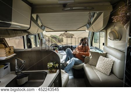 Adult Traveler Man Sit Down Inside Modern Cozy Mobile Home Camper Van Looking Nature Outside. Travel