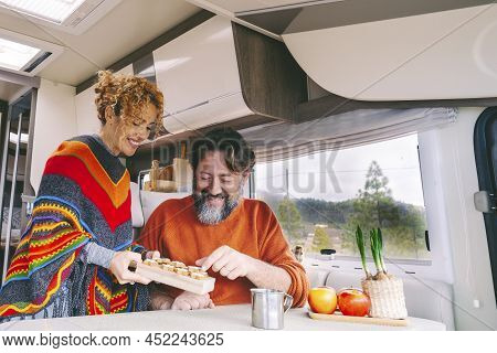 Couple Of People Enjoy Leisure Indoor In A Camper Camping Car. Adult Man And Woman Smile And Have Fu