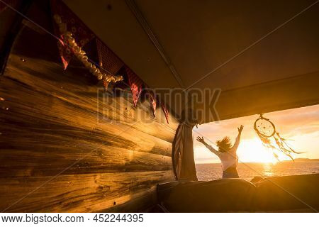 Overjoyed Tourist Jumping Against A Golden Sunset Light Viewed From Inside A Wooden Hand Made Classi