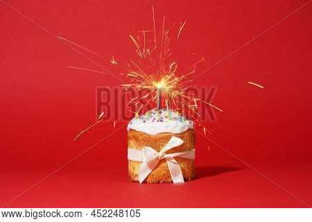 Easter Cake With Baw And Sparkler On Red Background, Easter Food. Minimal Concept