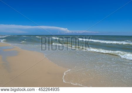 Sea Waves Wash The Beach Against A Blue Sky. Landscape On A Wild Beach. The Sea In The Summer.