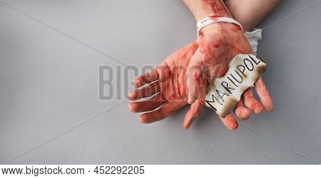 Bound Bloody Male Hands On A Gray Background Hold The Inscription City Of Mariupol. The Topic Of Kil