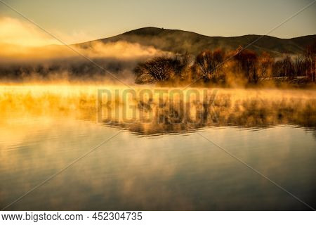 Moody Misty Low Cloud Over The Surface Of The Water At Sunrise Over Wairepo Arm Near Twizel
