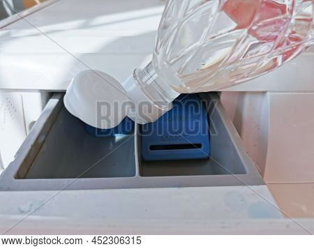 Close Up Hand Pouring The Vinegar Into The Front-loading Drawer. Clean A Washing Machine With Vinega