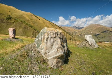 Sno, Georgia - September 21, 2021: Stone Faces sculptures in the Sno village in Caucasus mountains, Georgia. Stone carved sculptures represents the faces of the most famous artists of Georgia