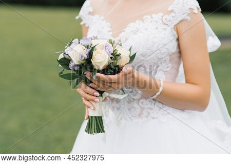 The Bride's Wedding Bouquet Of Milk Roses And Lilac Eustoms In The Hands Of The Bride Close-up