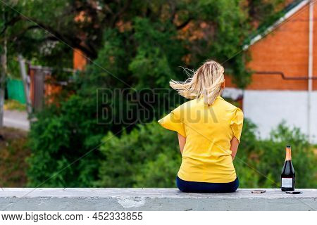 Back View Of Beautiful Blonde Girl. Near With Her Bottle Of Alcohol And Pack Of Cigarette Hair In Mo