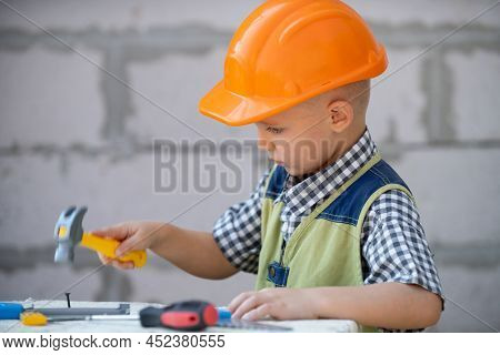 Kid In Hard Hat Holding Hammer. Little Child Helping With Toy Tools On Construciton Site. Kids With 