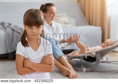 Portrait Of Offended Sad Little Girl Standing With Folded Hands, Looking At Camera With Sadness, Jea