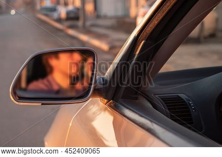 Man Drinking Alcohol While Driving In His Car On Sunset. Reflection In Mirror.