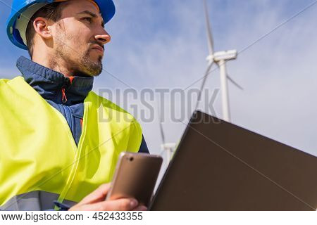 Close-up Of A Worker's Face Using His Troubleshooting Equipment In A Field Of Electric Wind Power Ge